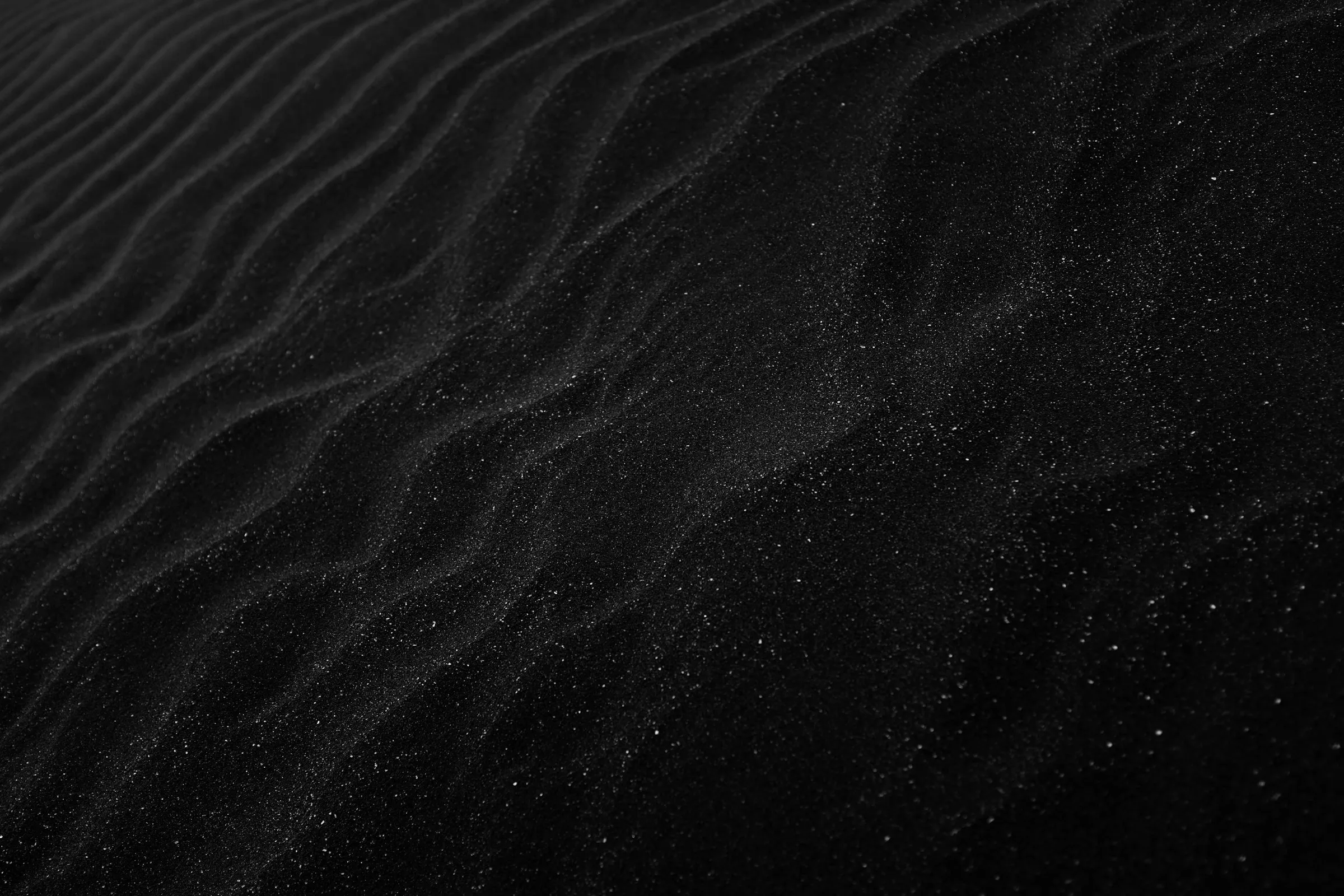 Wellenförmige Struktur in dunklem Sand